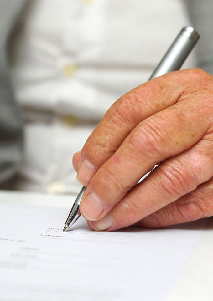 Senior woman's hands signing paper work