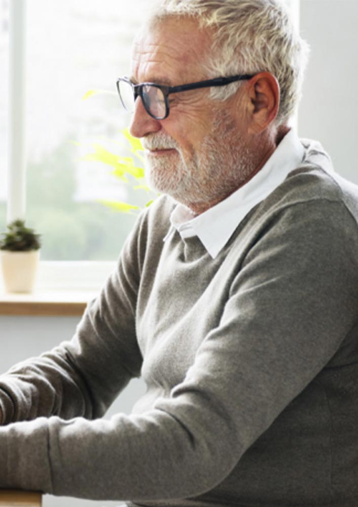 Image of an older man wearing a grey jumper at a desk