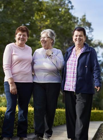 Photo of three women in a park smiling broadly