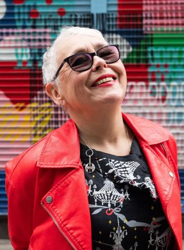 Image of an older women wearing a read leather jacket and glasses