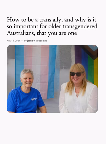 Two people sitting in front of the trans and rainbow flags