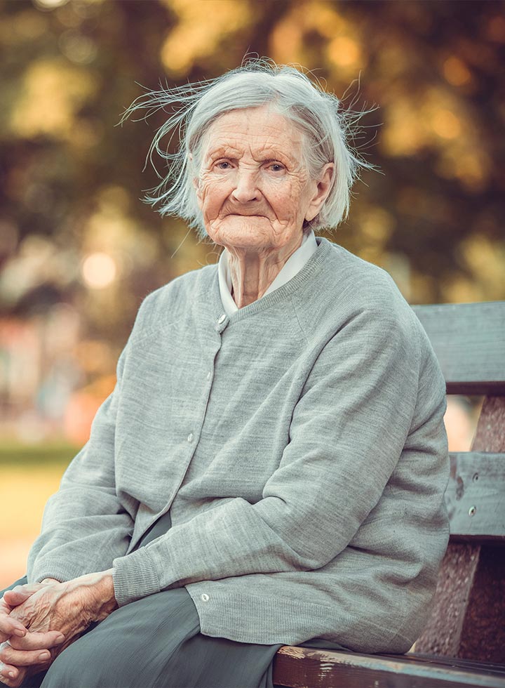 Photo of senior lady sitting on a park bench