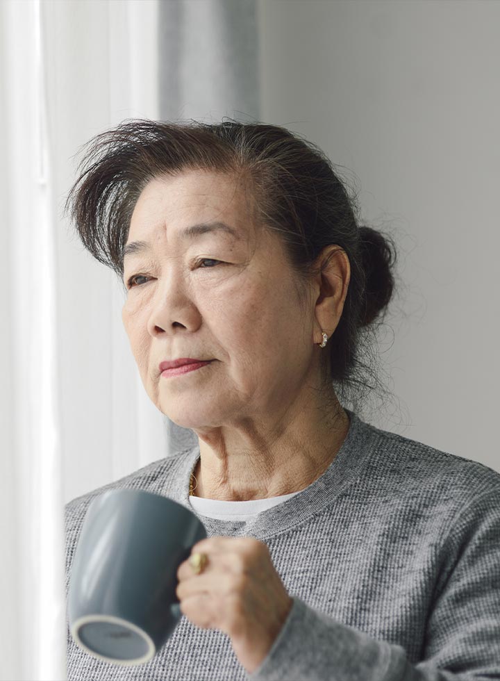 Photo of woman with grey mug looking out of window