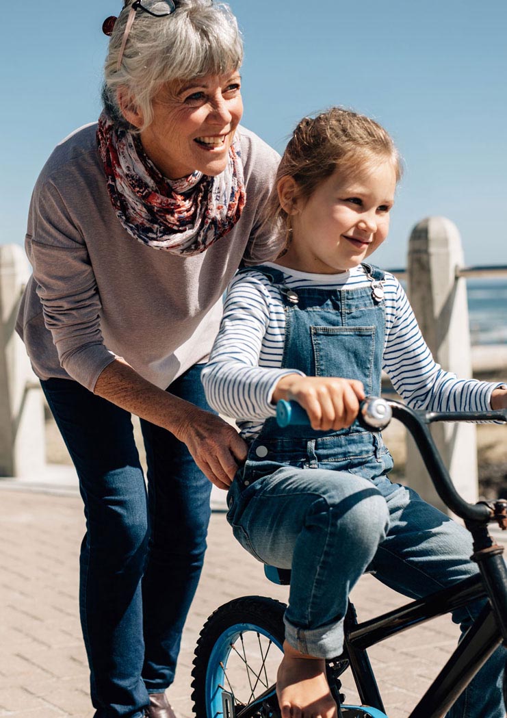 Grandmother teaching her granddaughter how to ride a bike
