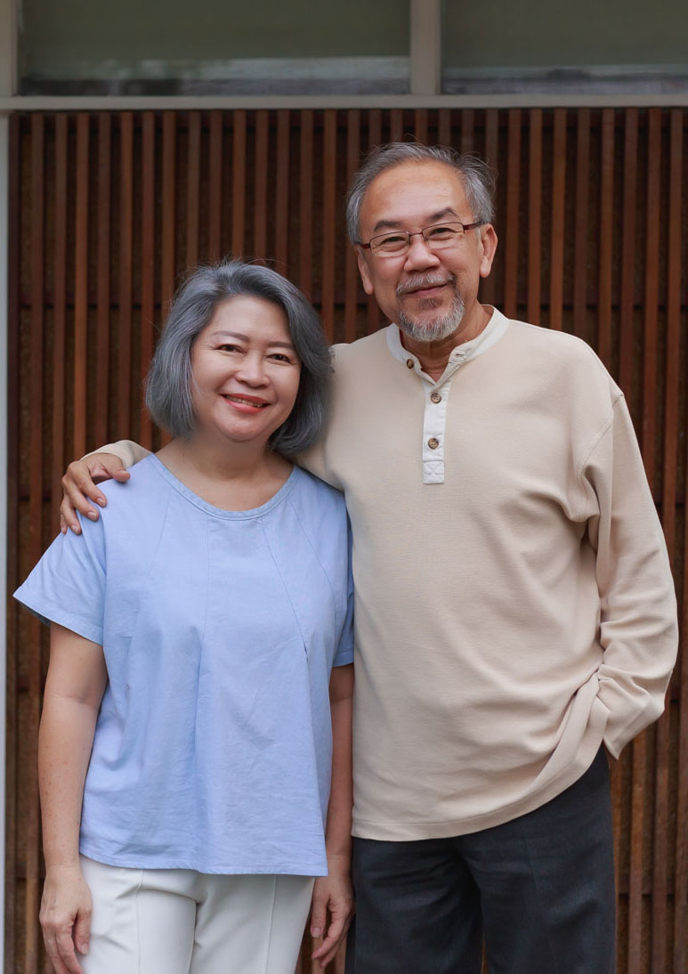 A senior couple standing in front of their house