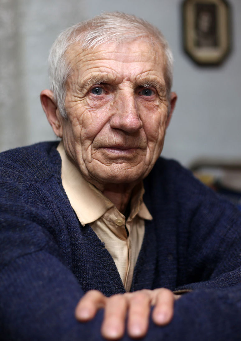 Senior man sitting at kitchen table looking at the camera