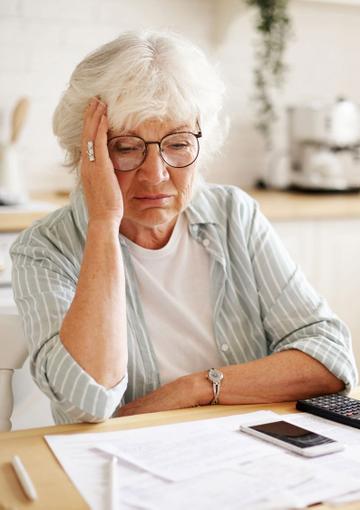 Stressed elderly woman with financial papers