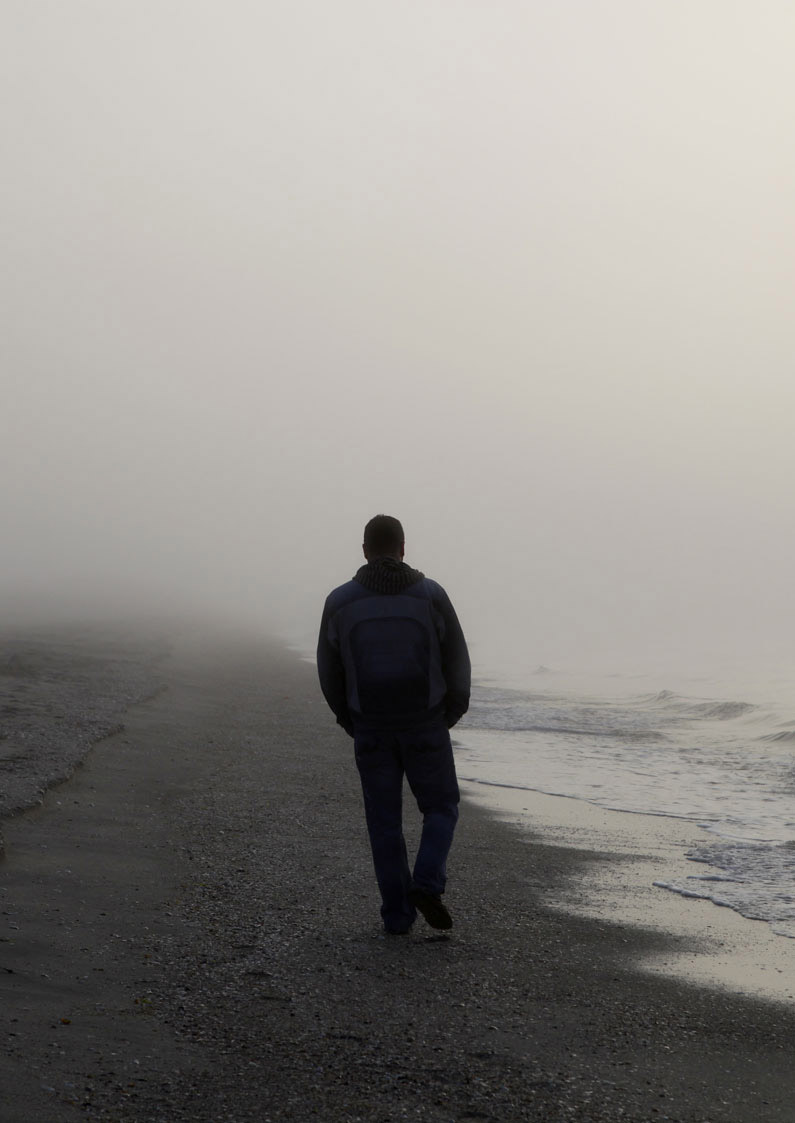 Man walking on the beach on a foggy morning 
