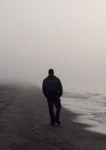 Man walking on the beach on a foggy morning 