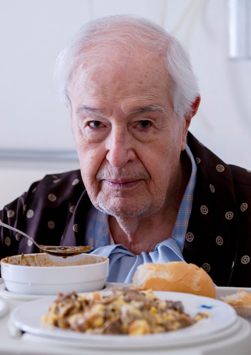 Senior man in a hospital bed and eating