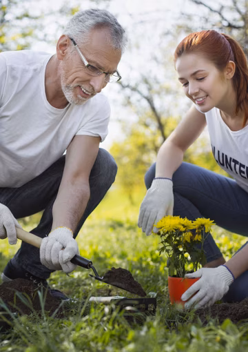 Senior man planting trees with young volunteers 