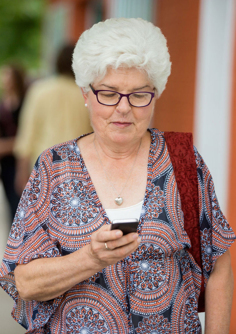Senior woman walking while looking at her phone