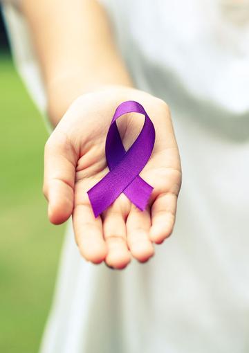 Hand holding out purple ribbon