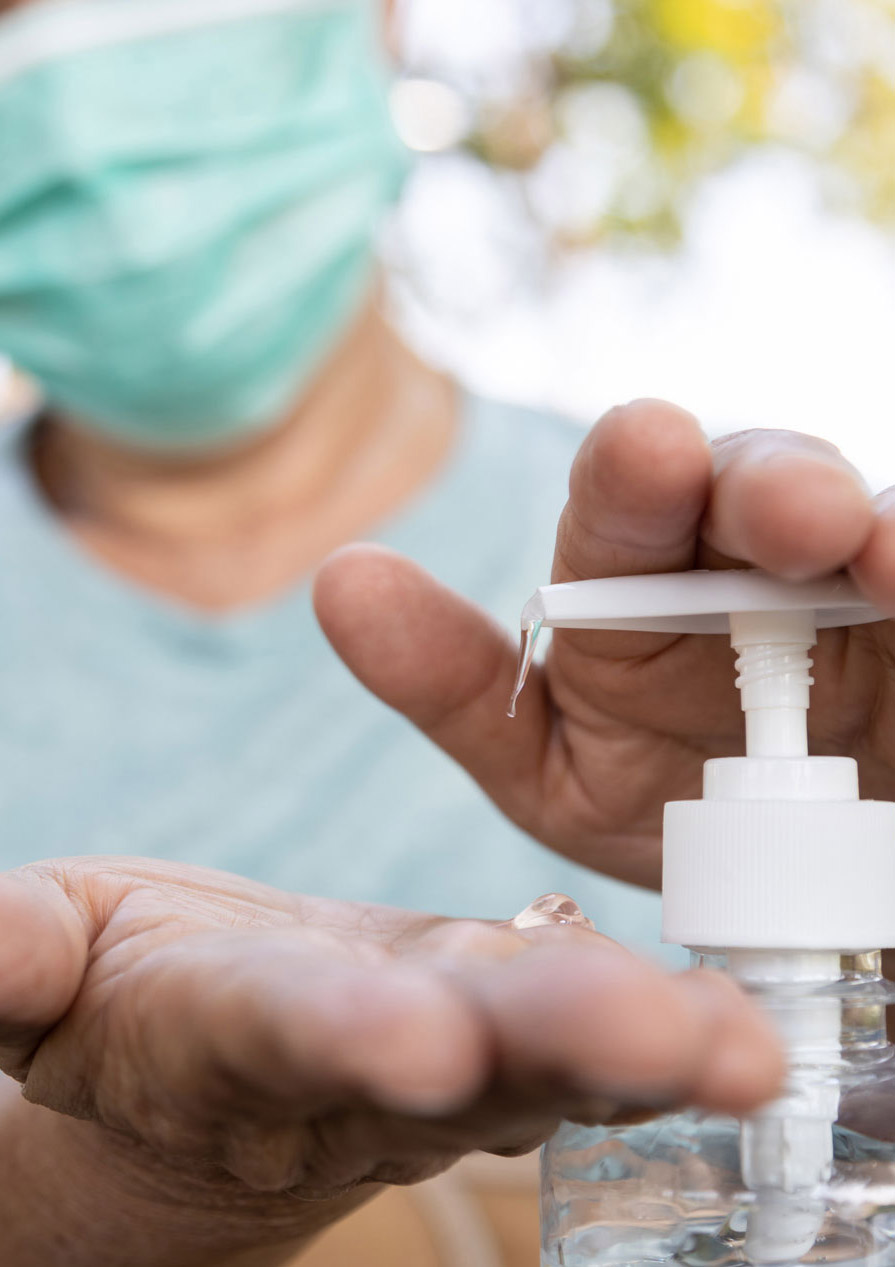 Masked senior woman applying hand sanitiser 