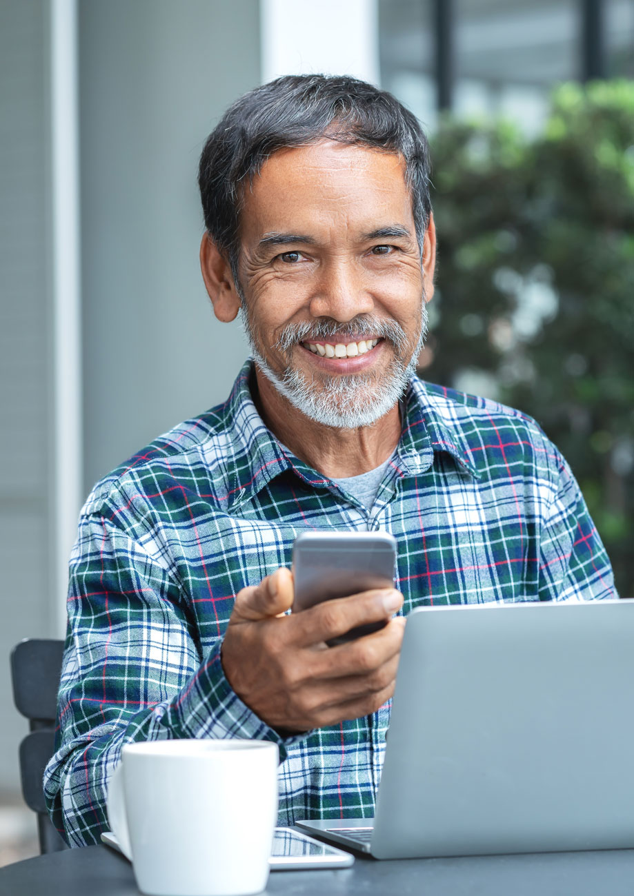 Senior man using phone and laptop