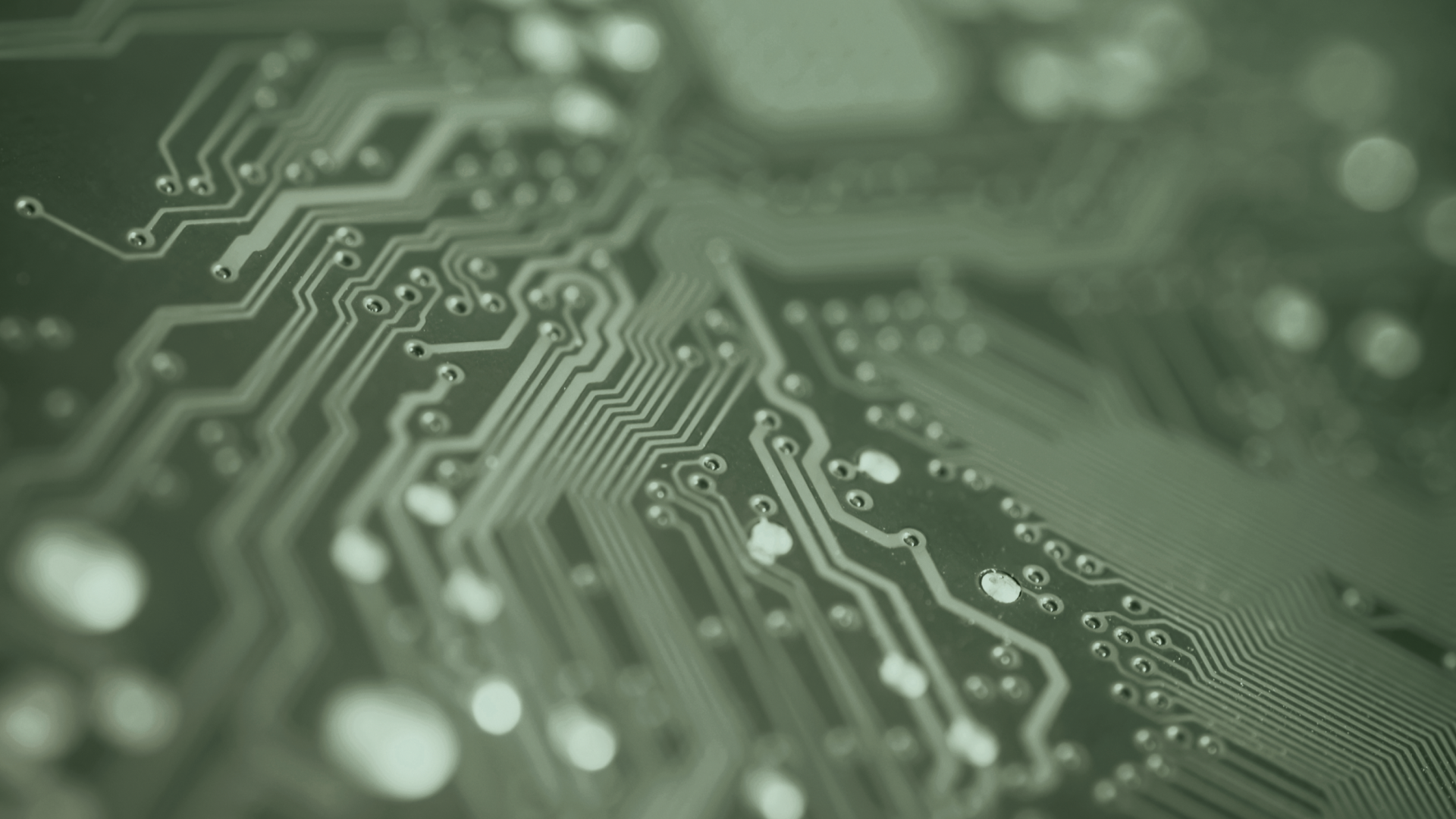 Close-up of a green printed circuit board showing intricate pathways and solder joints.