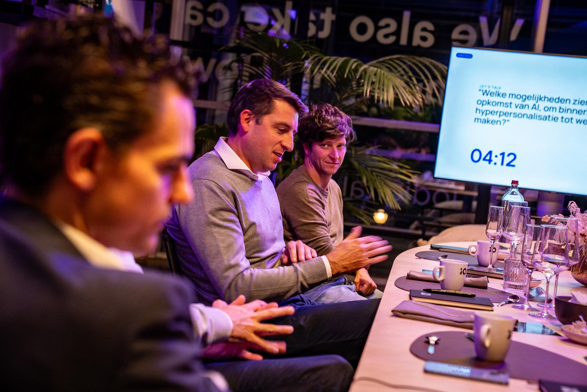 People engaged in a discussion at a conference table, with a screen displaying a topic about AI opportunities and a timer showing 04:12.