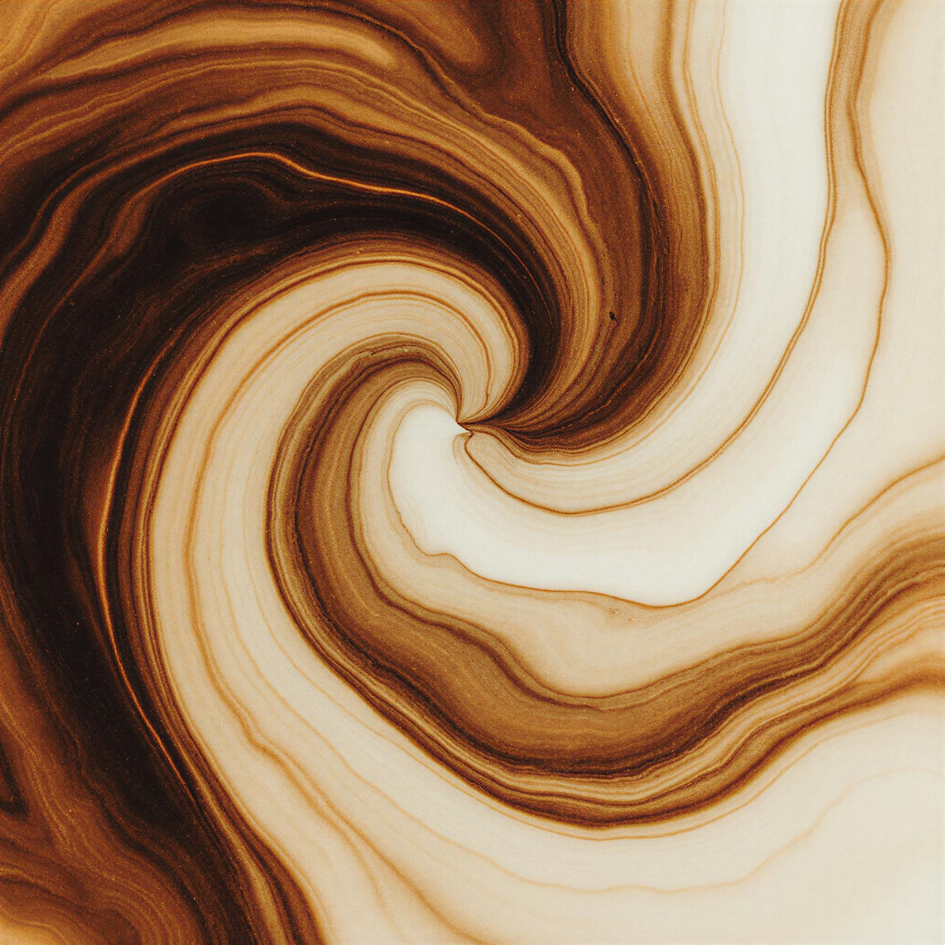 Abstract swirling pattern in warm brown, cream, and beige tones creating a dynamic spiral movement resembling natural wood grain or marble veining