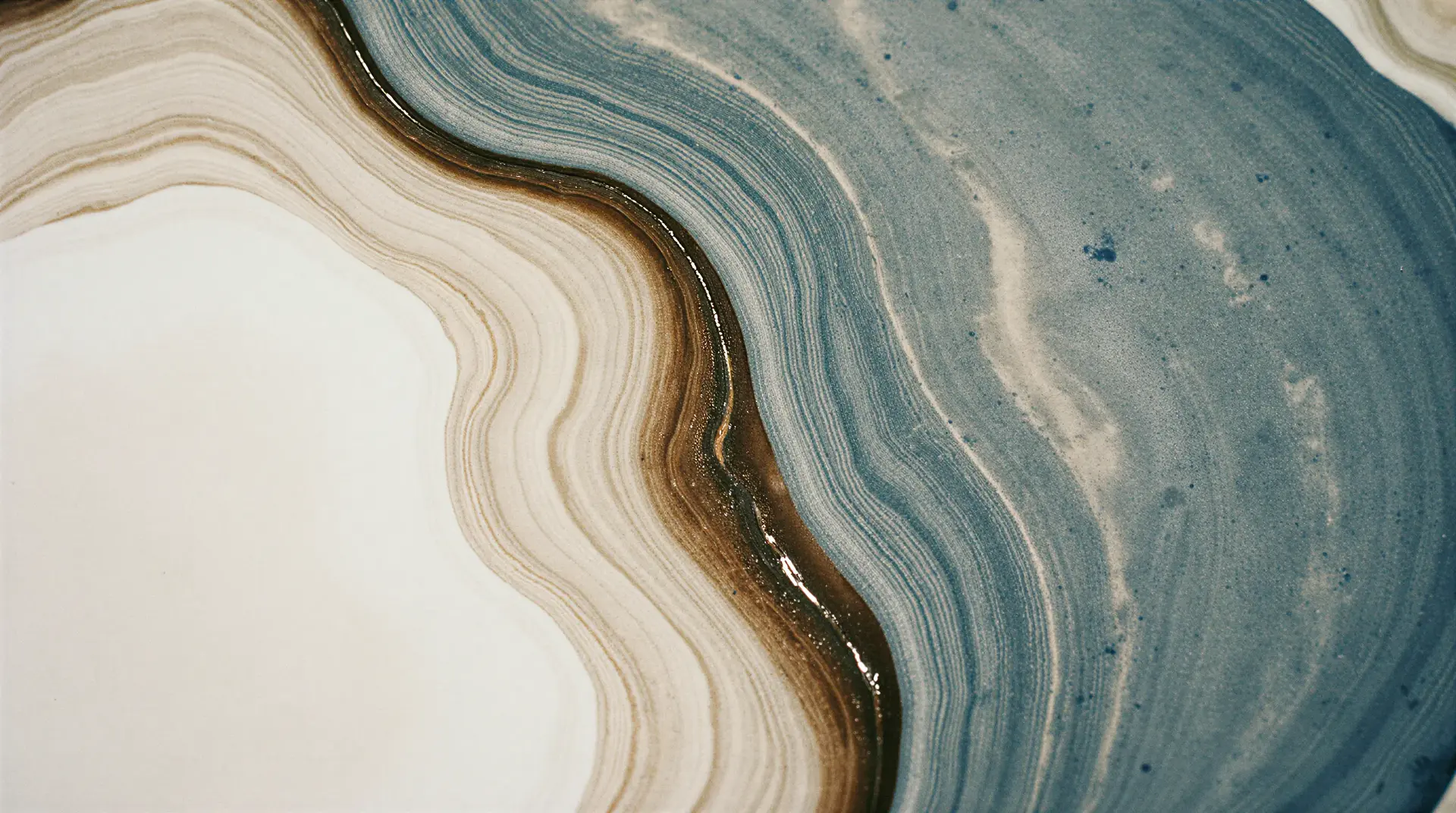 Abstract image of wavy, layered patterns in beige, brown, and blue tones, resembling a geological cross-section or marble texture.