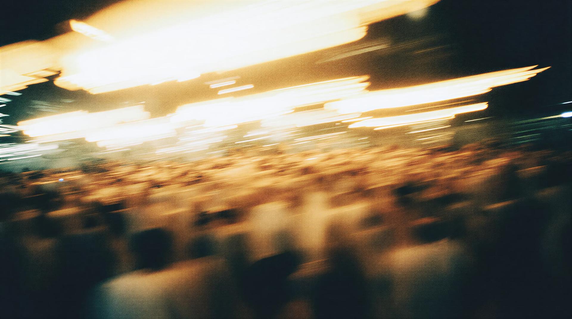 Abstract image of a blurred crowd with streaks of bright lights, creating a dynamic and energetic atmosphere.
