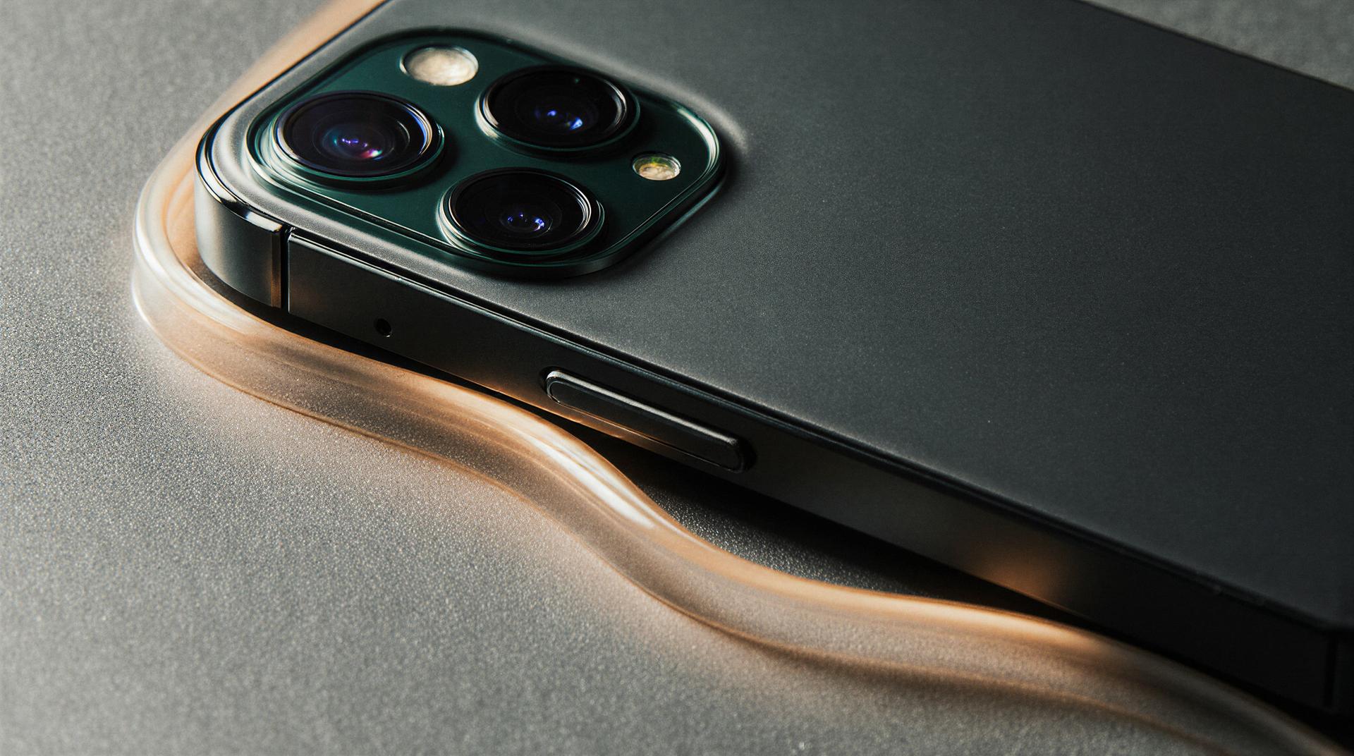 Close-up of a smartphone with a triple camera setup, resting on a wavy, translucent surface, highlighting its sleek design.