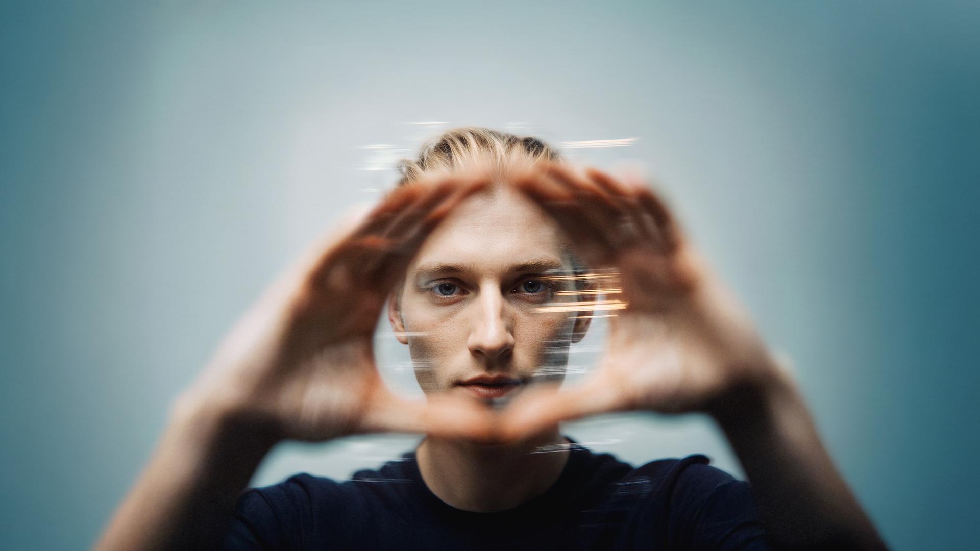 Person holding a transparent, circular object, creating a blurred, dynamic effect against a blue background.