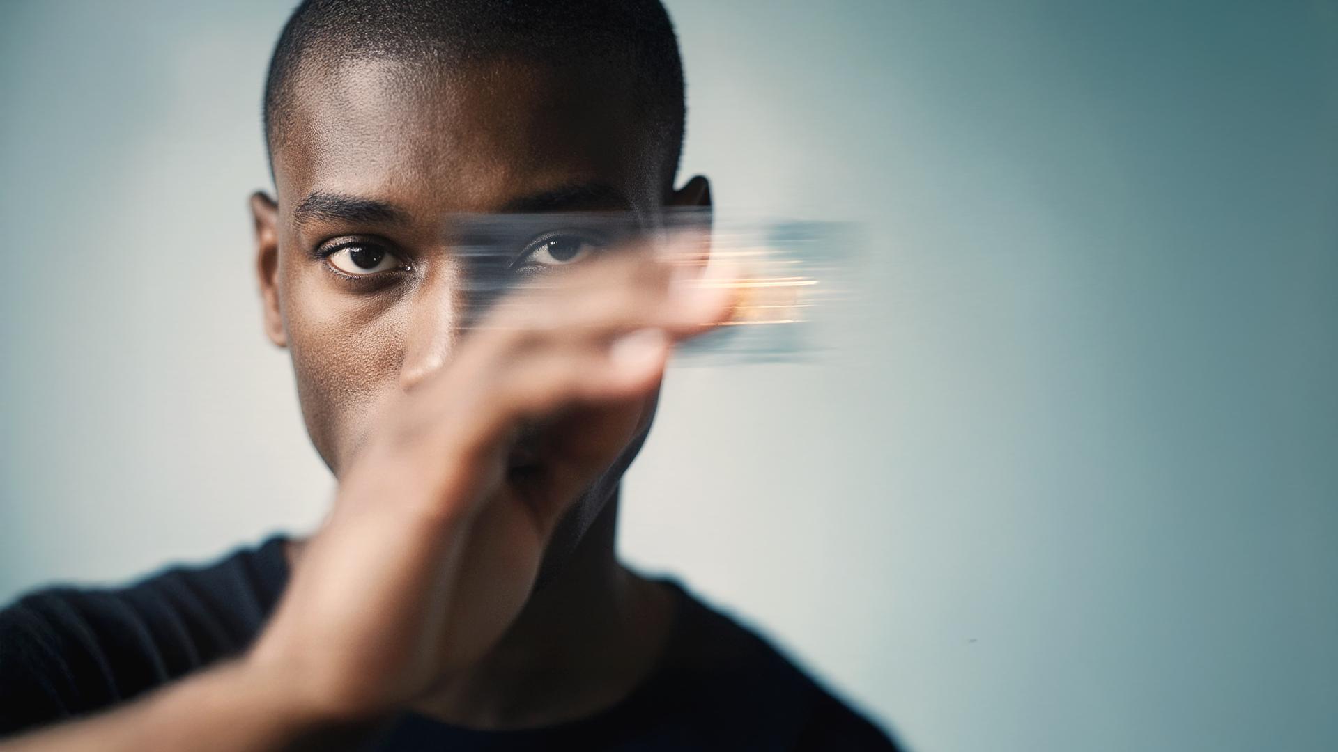 A person blurs a credit card in front of their face, set against a soft blue background.