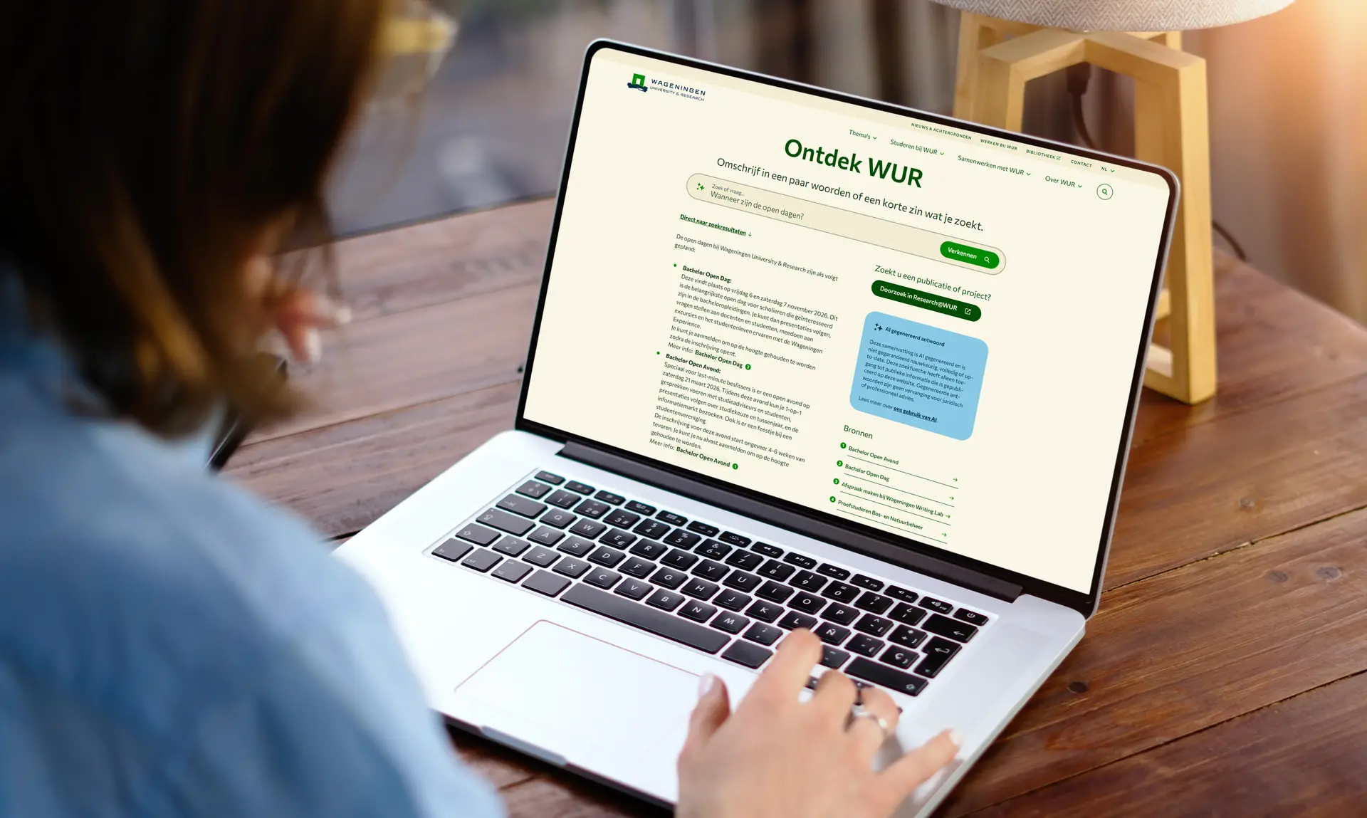 Person browsing the Wageningen University & Research website on a laptop at a wooden desk.