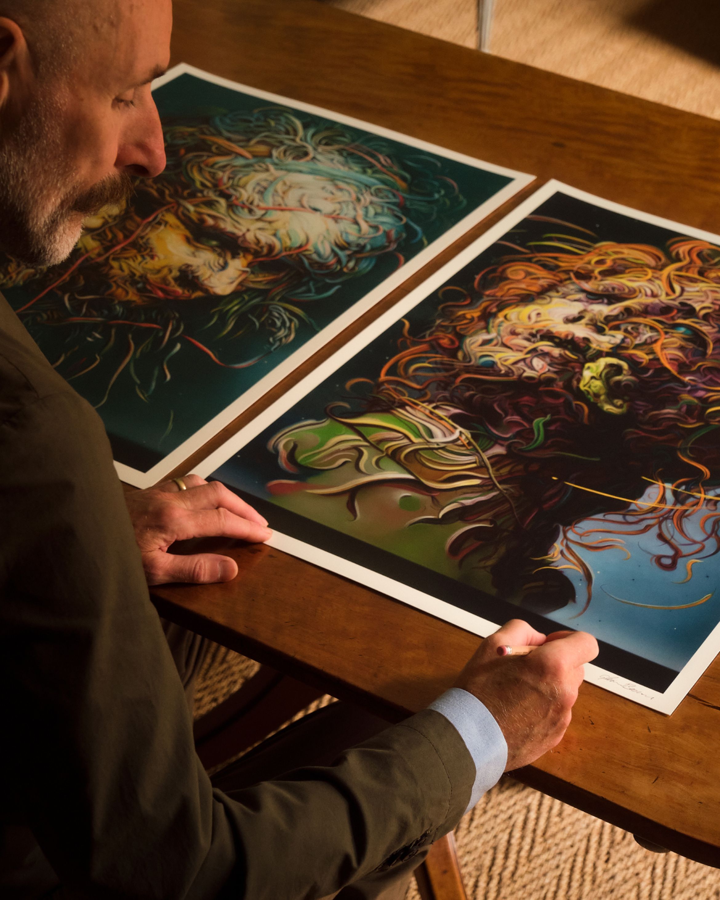 A close-up of Glenn Brown signing a pair of new limited edition prints