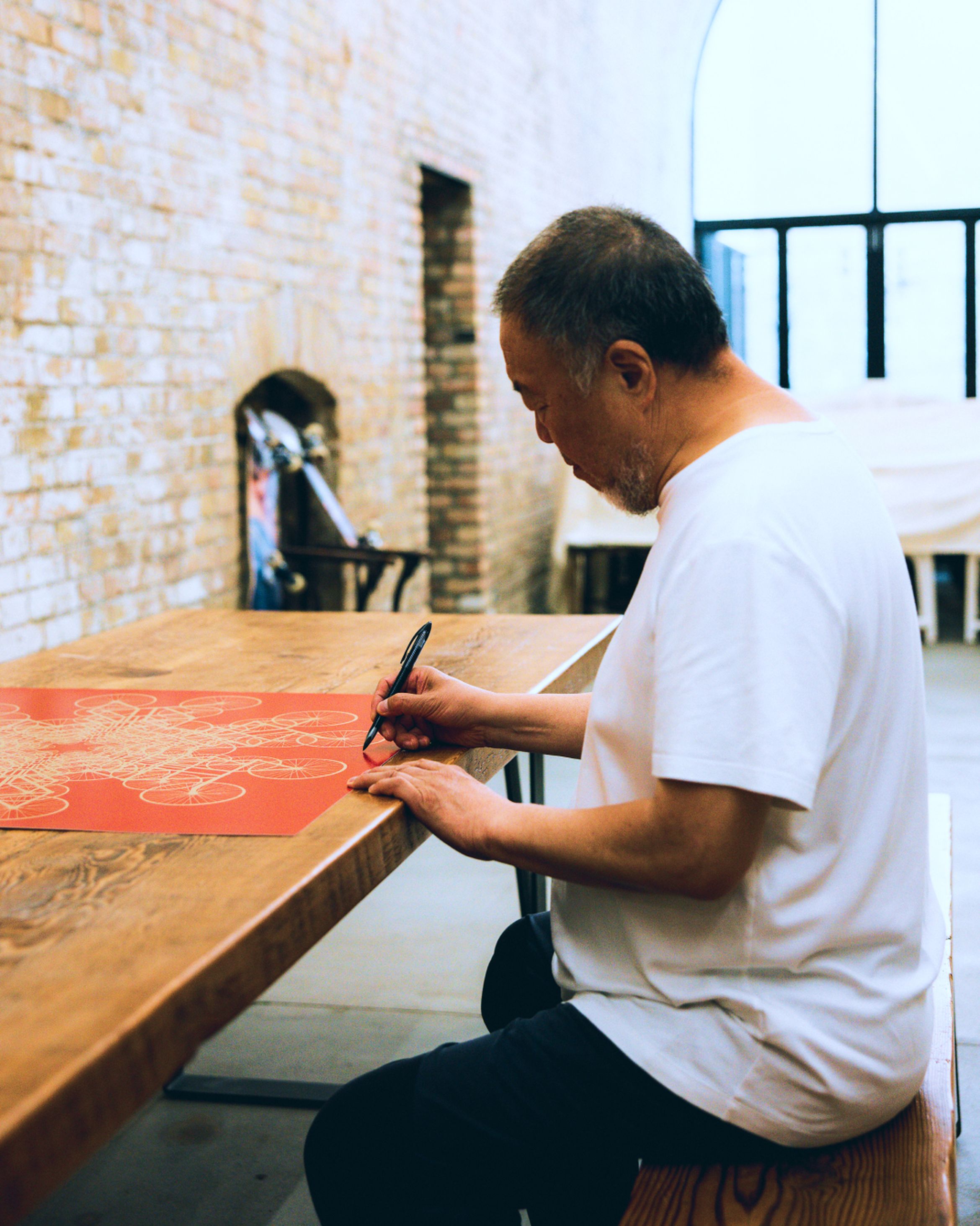 An image of artist Ai Weiwei signing the 'Forver Bicycle' print in his studio.