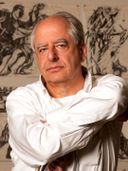 Artist William Kentridge sitting in a white shirt in from of monochrome drawings Artist William Kentridge sitting in a white shirt in from of monochrome drawings