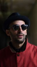 Close up of JR in a red coat, sunglasses and a hat Close up of JR in a red coat, sunglasses and a hat