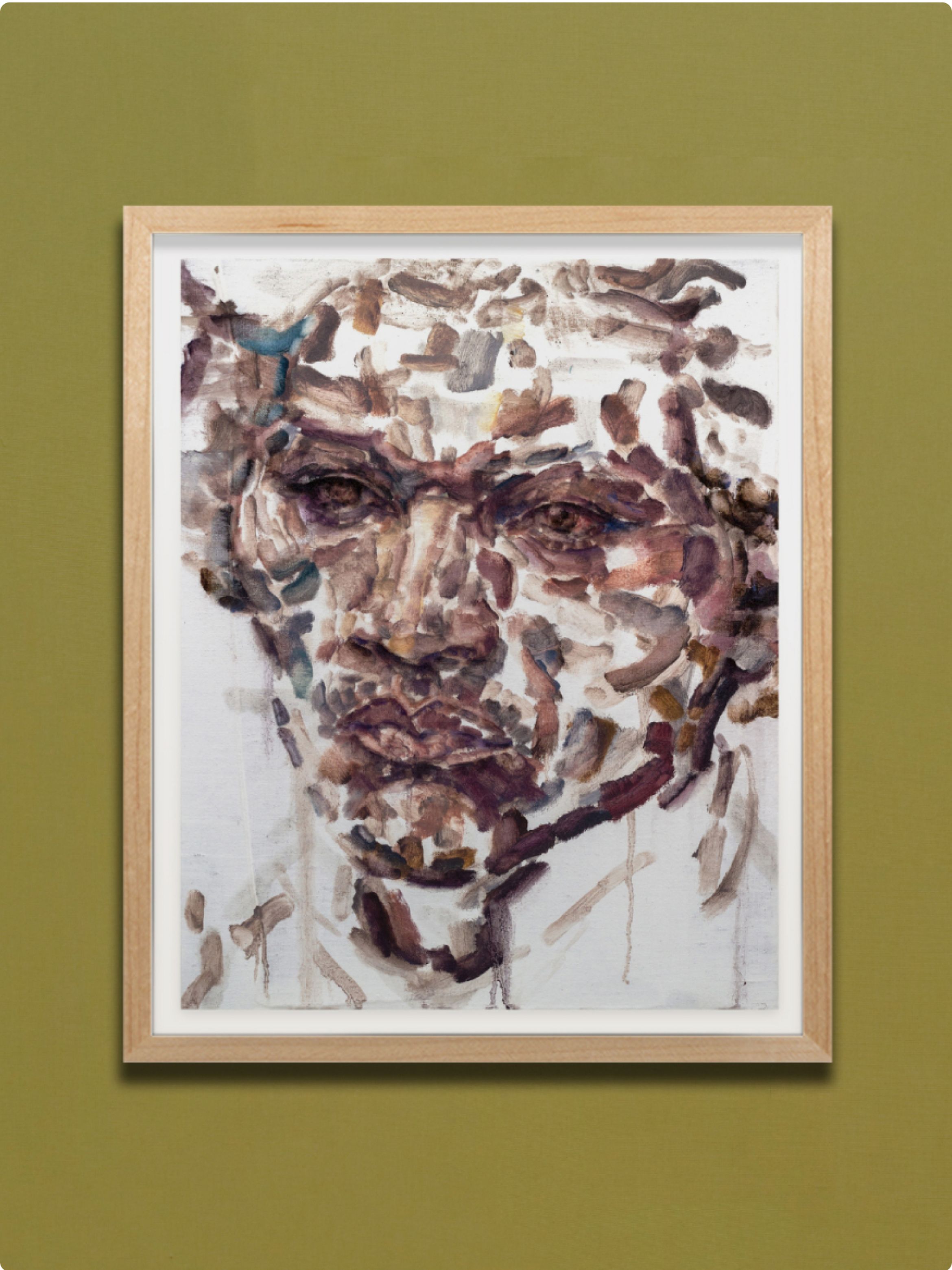 Abstract painting of a face in earthy tones, with bold brush strokes, in a light wooden frame on a green wall.
