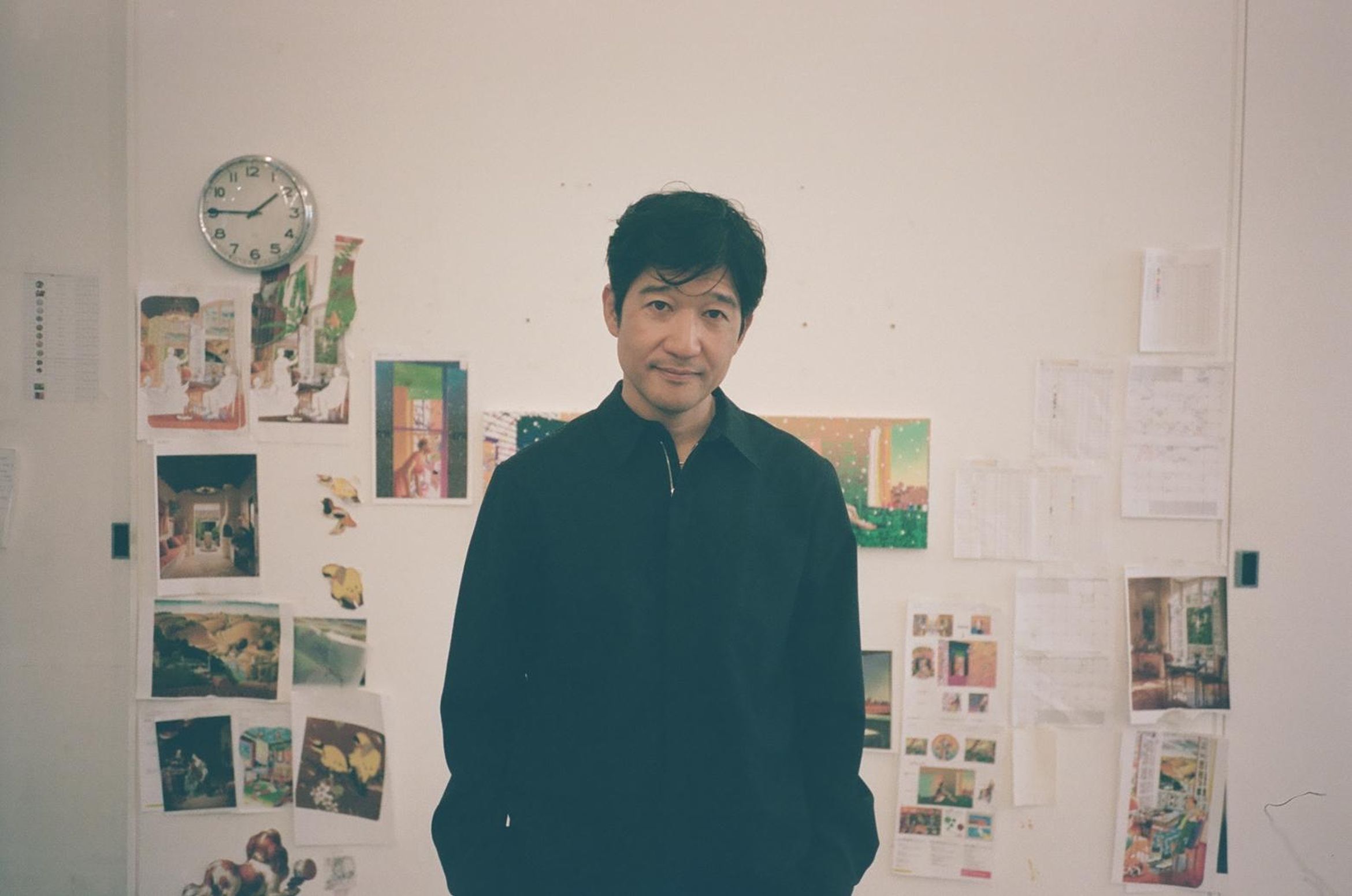 Matsu stands before studio wall with preparations for exhibition