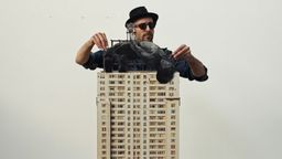artist JR wearing sunglasses and a hat, adjusting the placement of the figure on his edition of sculptures – GIANTS, High jump in Rio artist JR wearing sunglasses and a hat, adjusting the placement of the figure on his edition of sculptures – GIANTS, High jump in Rio
