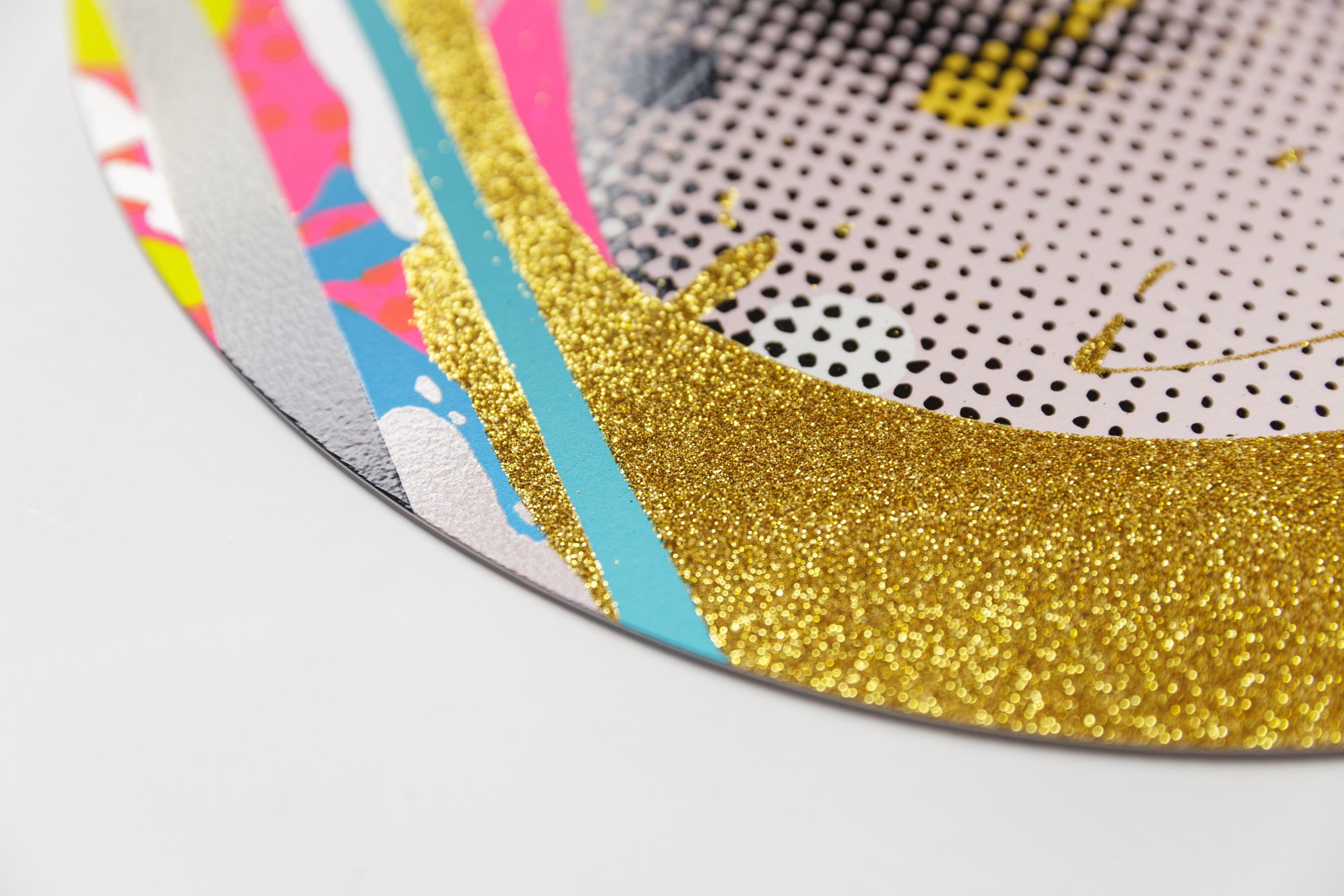 Detail of a corner of a print with gold glitter edge and blue, pink and white stripes