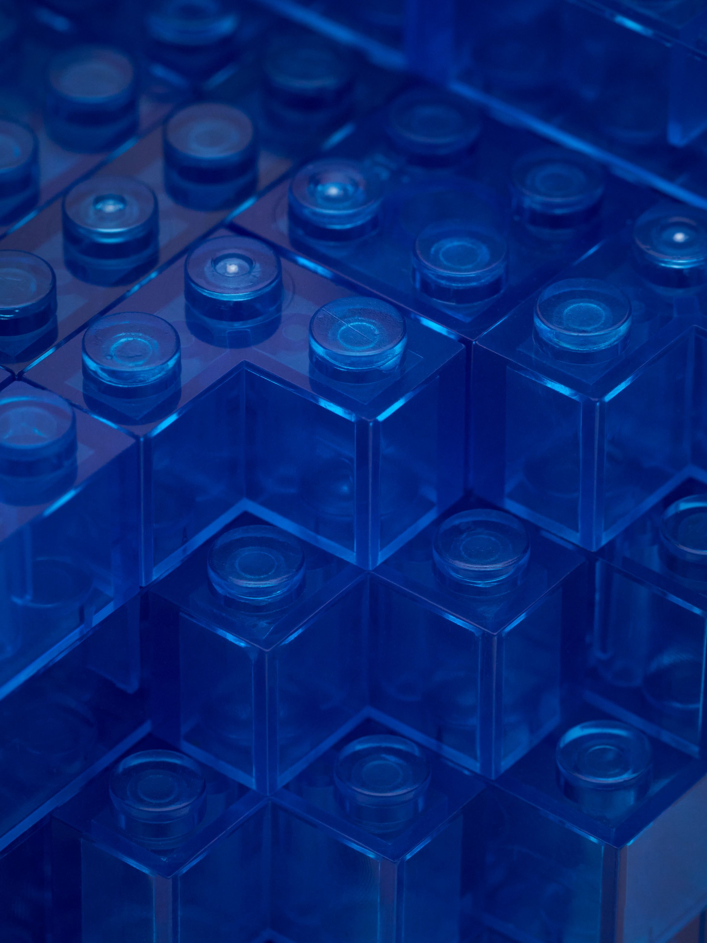 Close-up of interlocking translucent blue plastic bricks stacked together. Close-up of interlocking translucent blue plastic bricks stacked together.