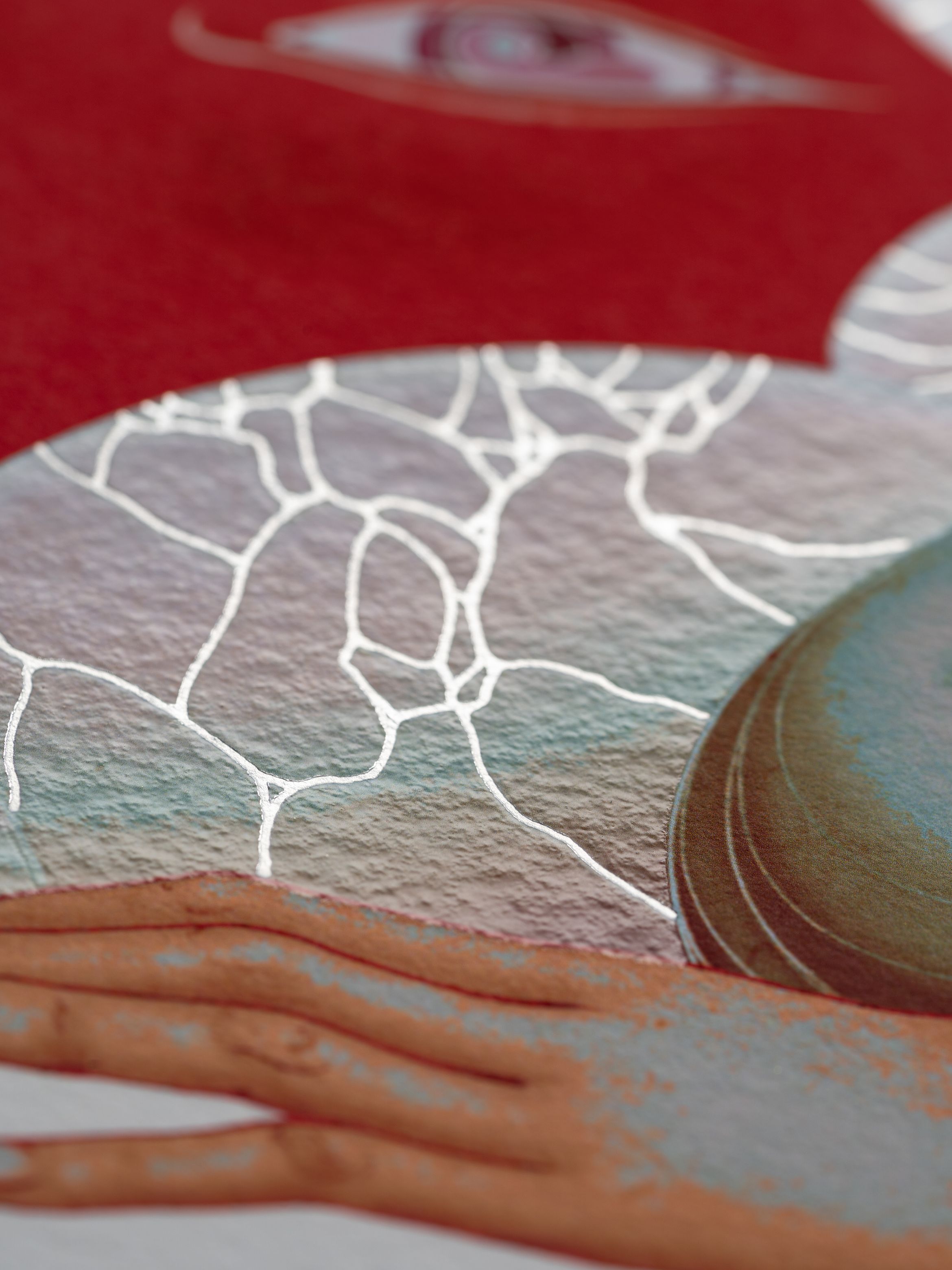 A textured abstract image featuring a hand, cracked pattern, circular shape, and an eye on a red background.