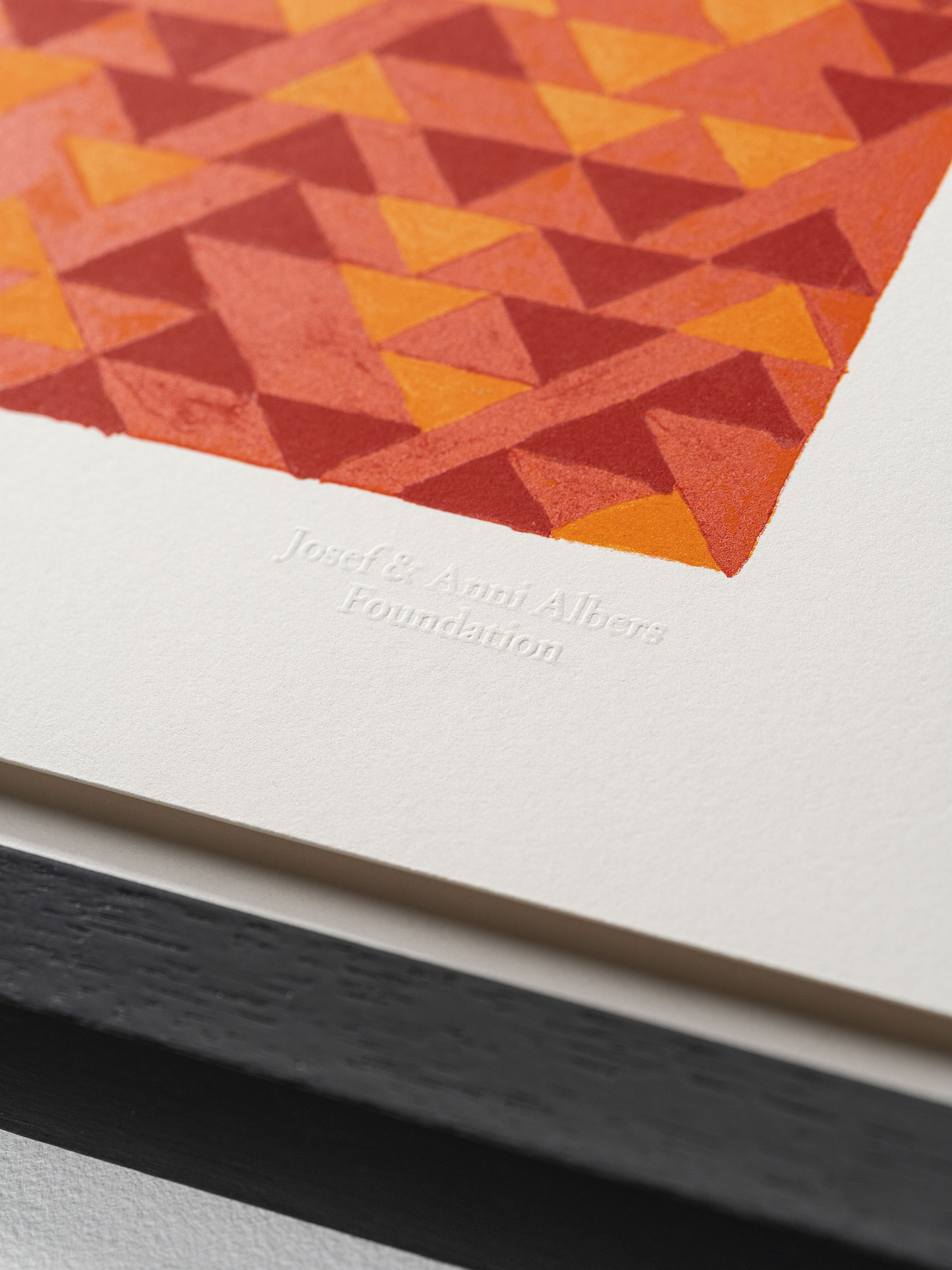 Close-up of a geometric artwork in red and orange triangles, with "Josef & Anni Albers Foundation" embossed on the white border.