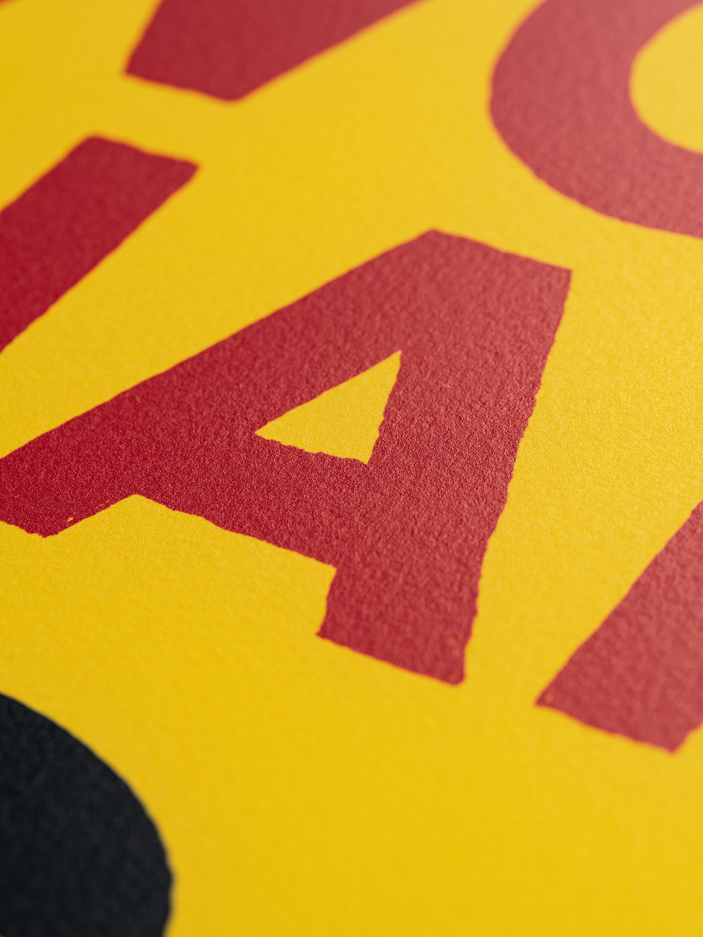 Close-up of bold red letters on a textured yellow background, showing part of the word "LA".