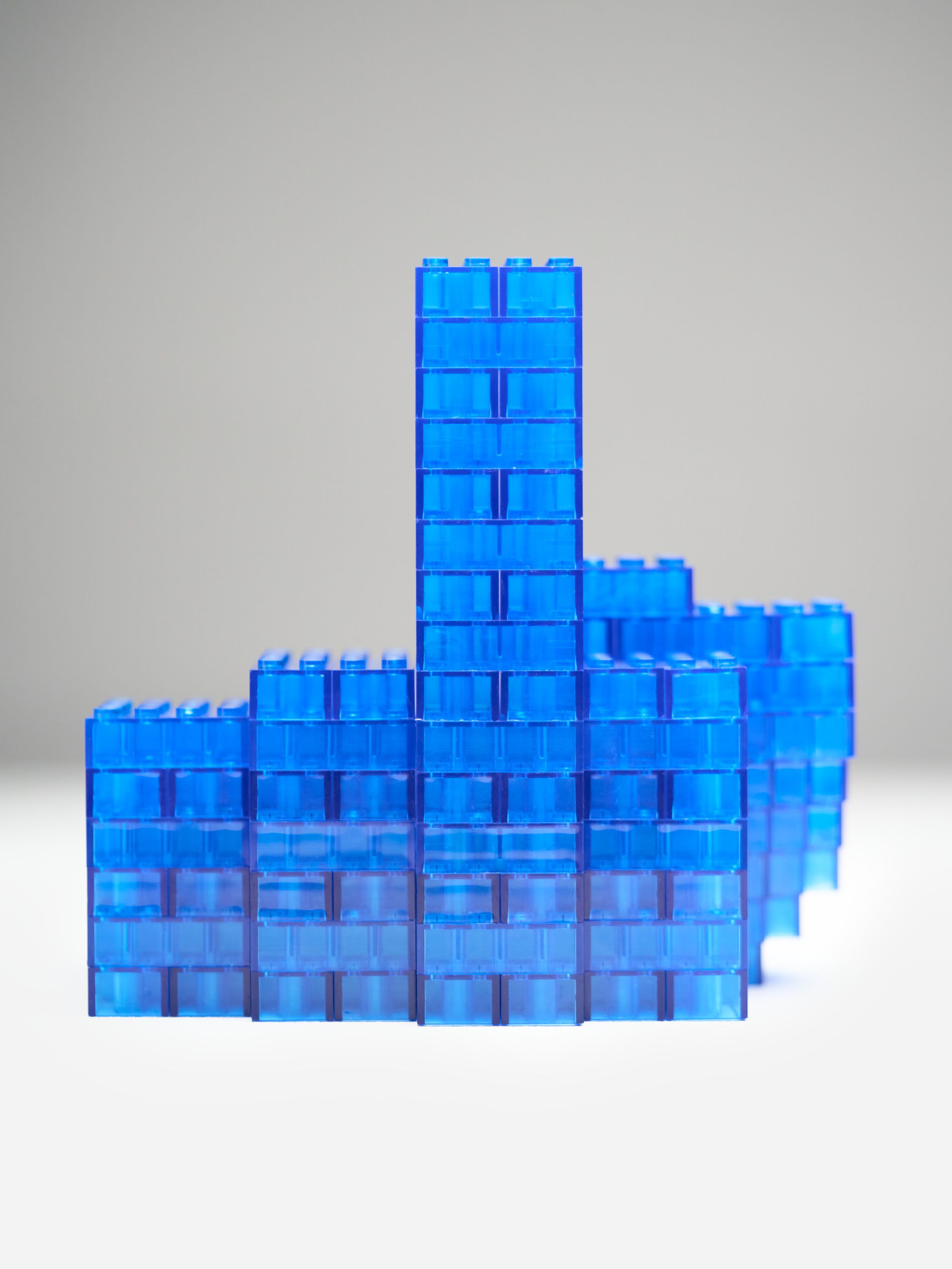 Stacked blue translucent toy blocks forming a stepped structure against a neutral background.