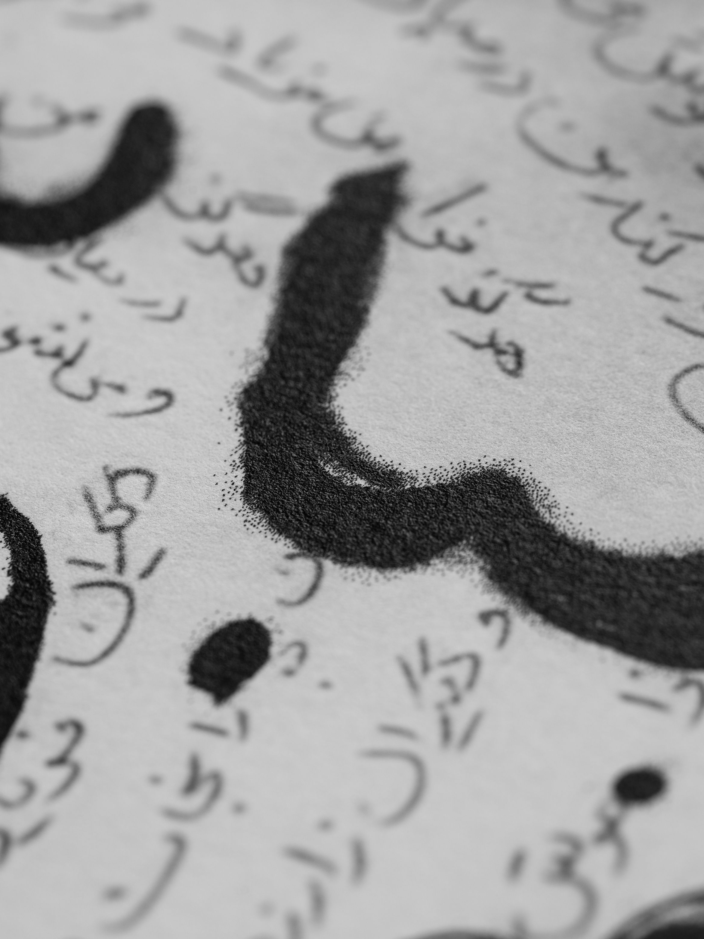 Close-up of artistic Arabic calligraphy in black ink, featuring smooth, bold strokes and intricate detailing.