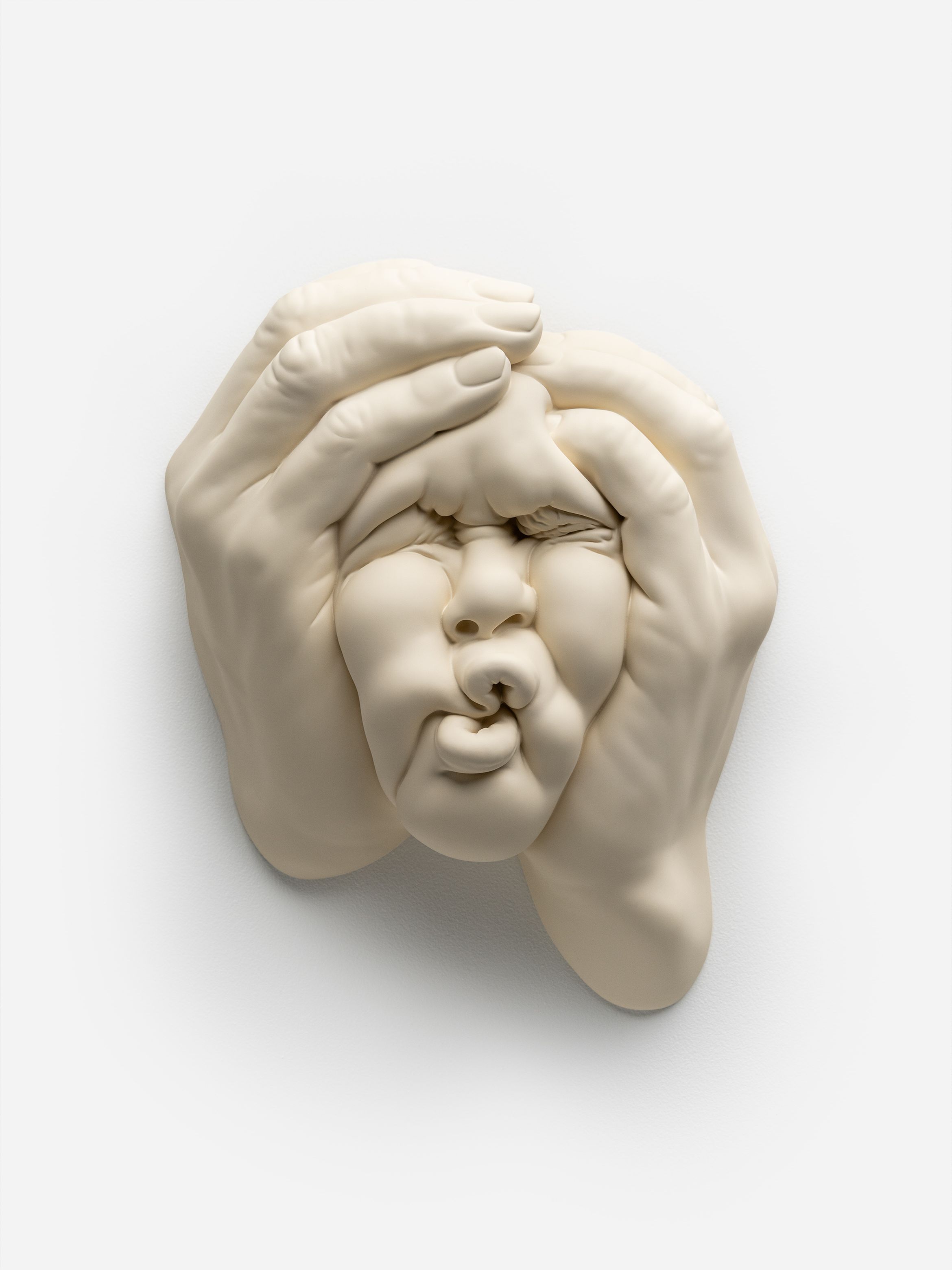 Sculpture of a face being squeezed by hands, with distorted features and a neutral background. Sculpture of a face being squeezed by hands, with distorted features and a neutral background.