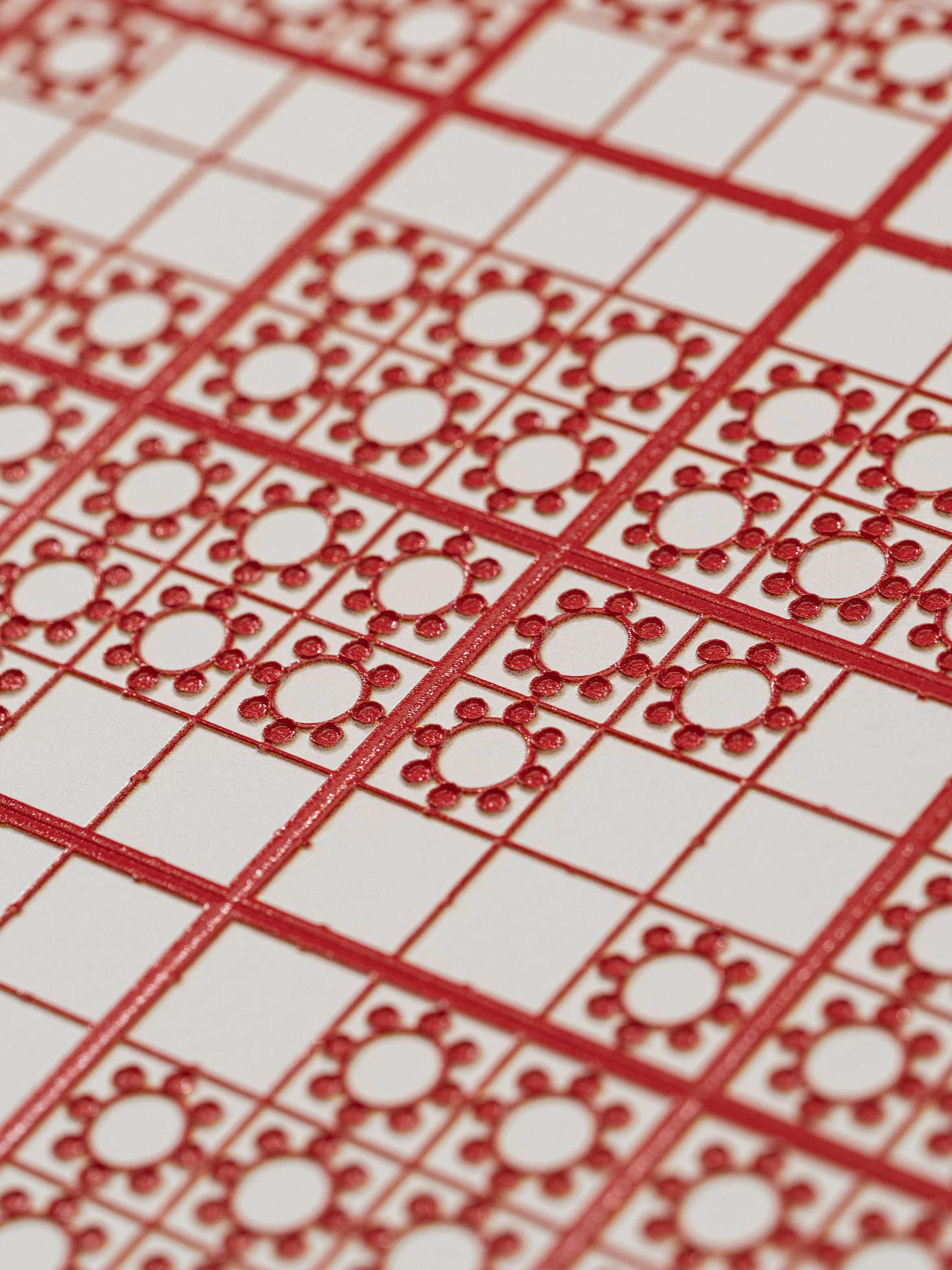Close-up of a red and white grid pattern with circular and square designs, featuring detailed geometric shapes.