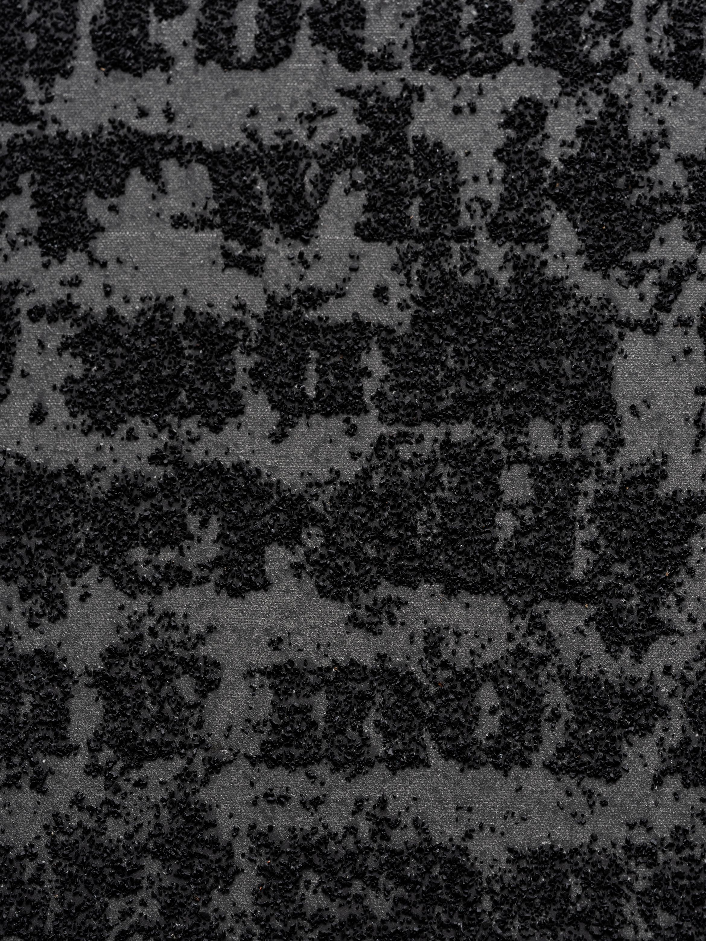 Abstract texture with black granules forming a random pattern on a gray fabric background.