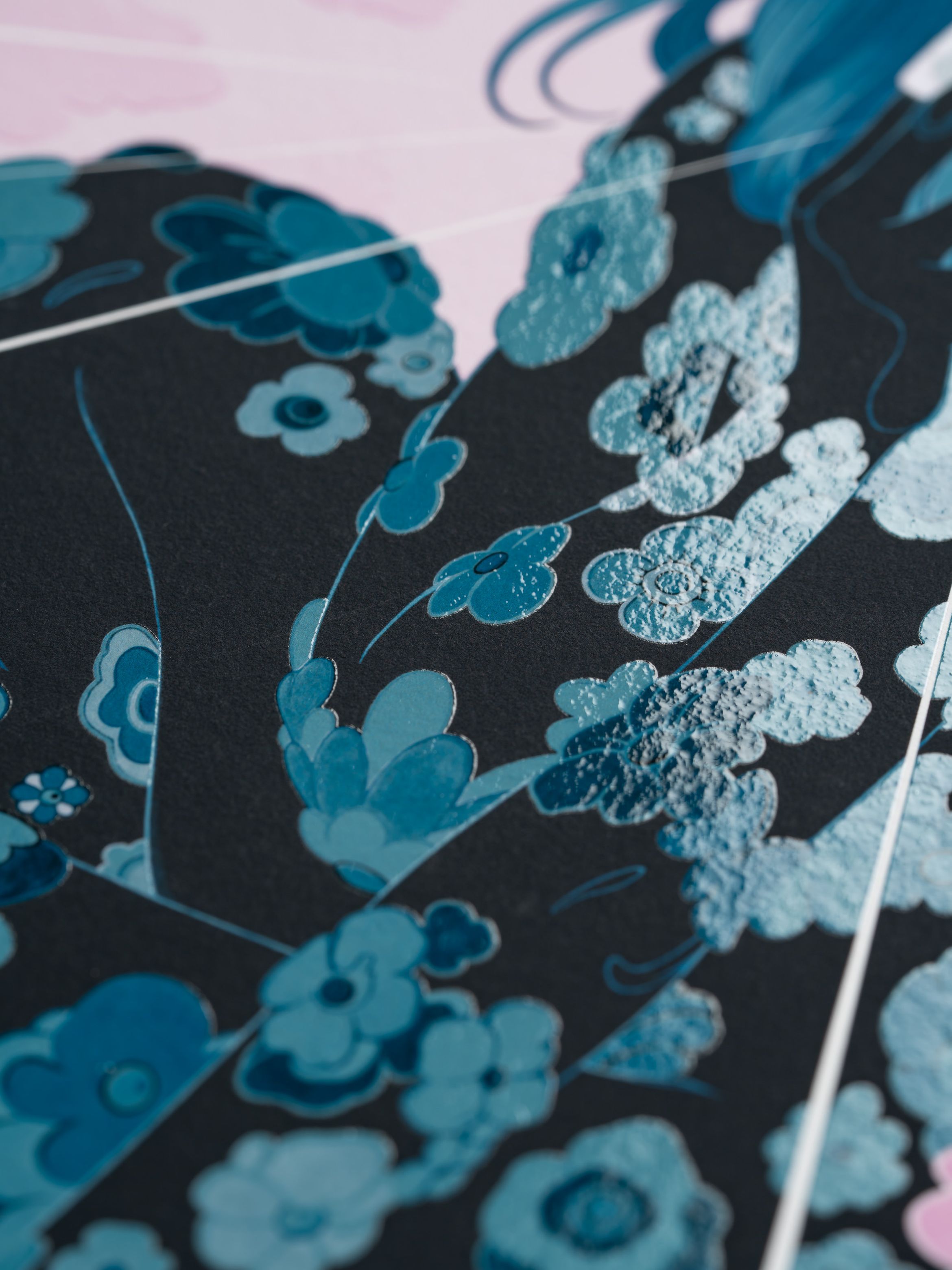 Close-up of a floral design with blue and teal flowers on a dark background, featuring textured and glossy elements.