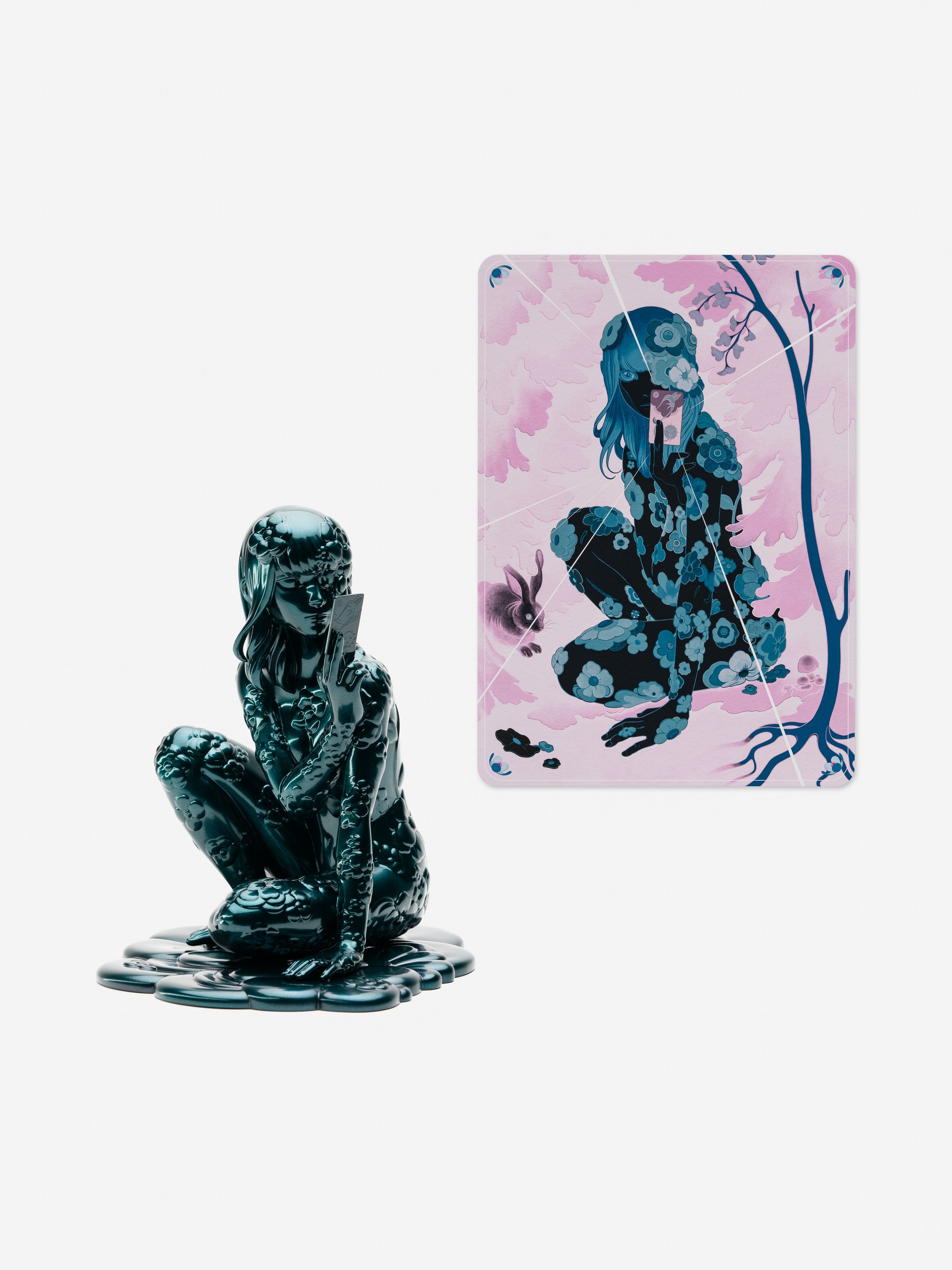 A reflective sculpture of a crouching figure holding a card, paired with a pink and purple illustration of the same pose.