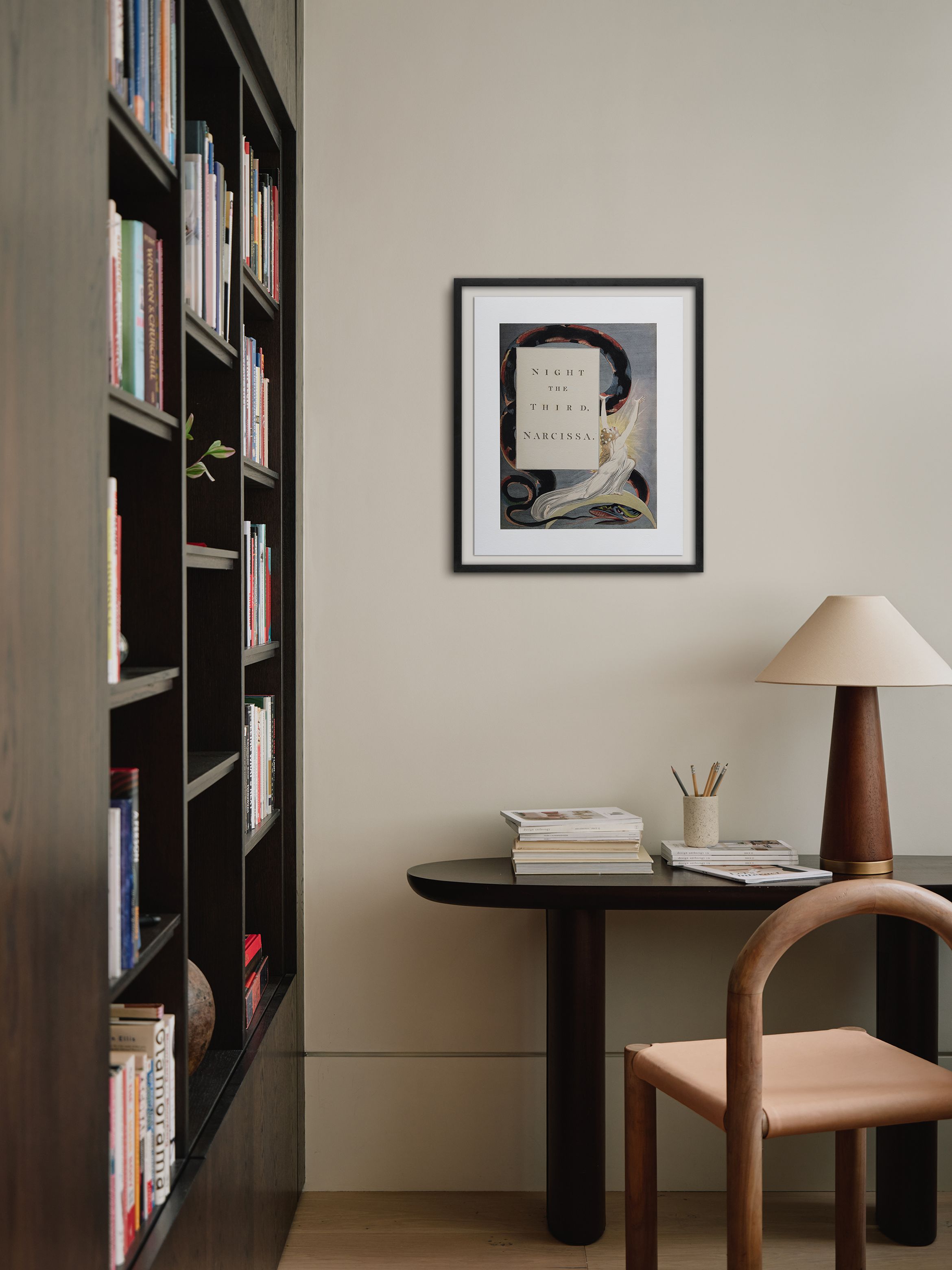 Cosy study nook with a wooden desk, chair, lamp, and bookshelves. Framed art on the wall adds a touch of elegance.