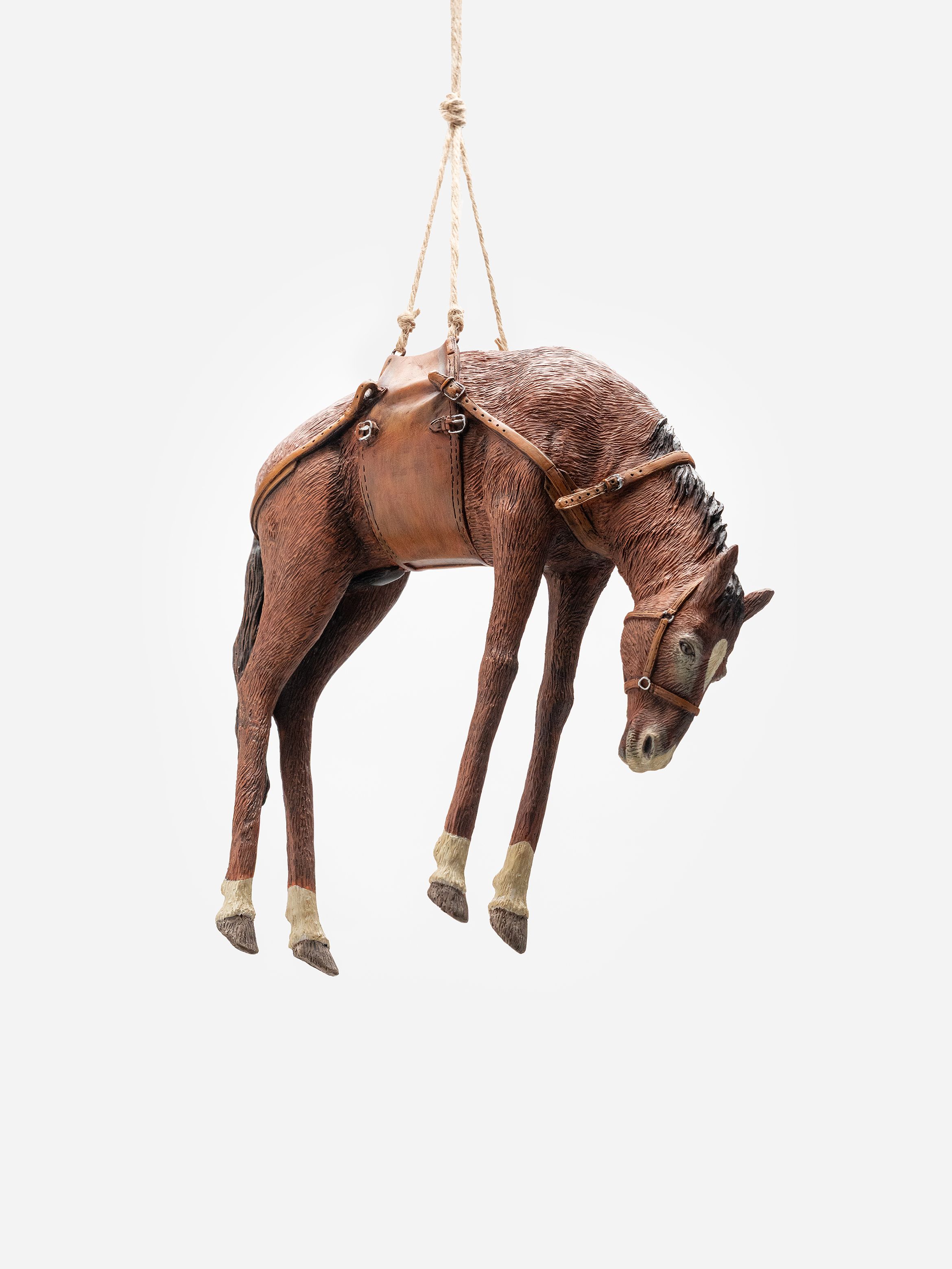 A realistic model of a brown horse, suspended in mid-air by a rope harness, against a plain white background. A realistic model of a brown horse, suspended in mid-air by a rope harness, against a plain white background.