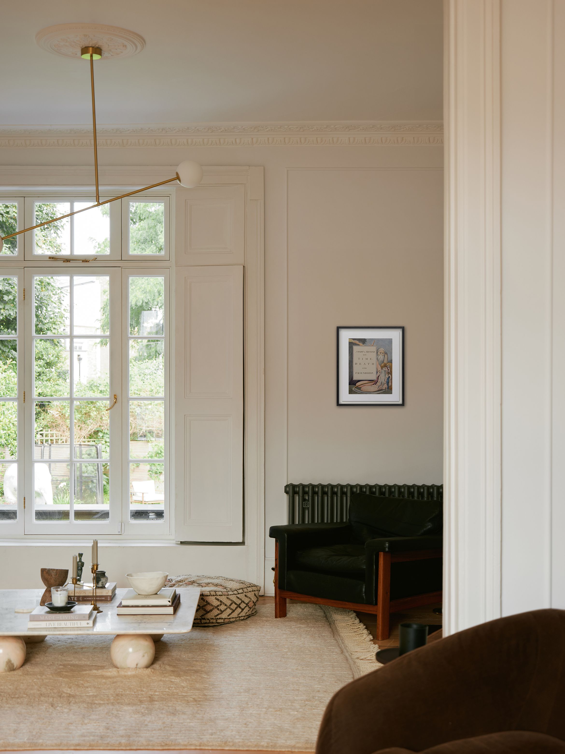 Elegant living room with large windows, a modern chandelier, a black armchair, and a low wooden coffee table on a beige rug.